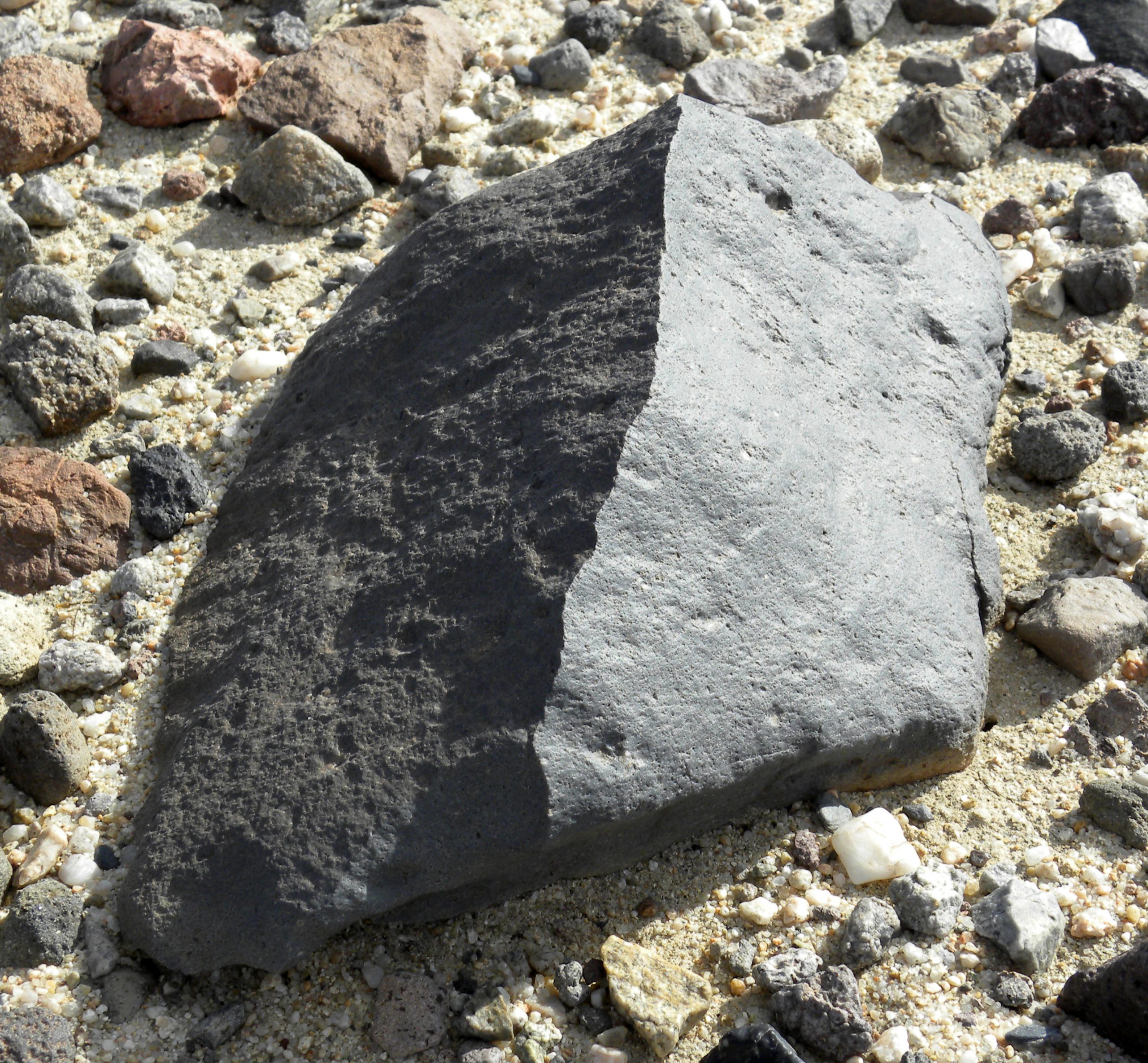 Rock on desert floor polished on multiple sides by sandblasting.